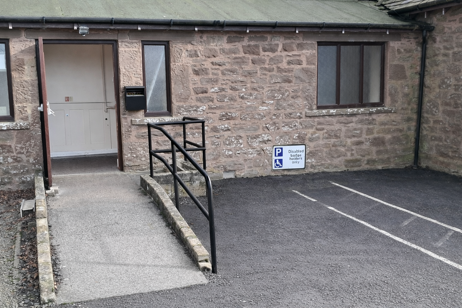 Ramp access adjacent to disabled parking area to the rear of the building